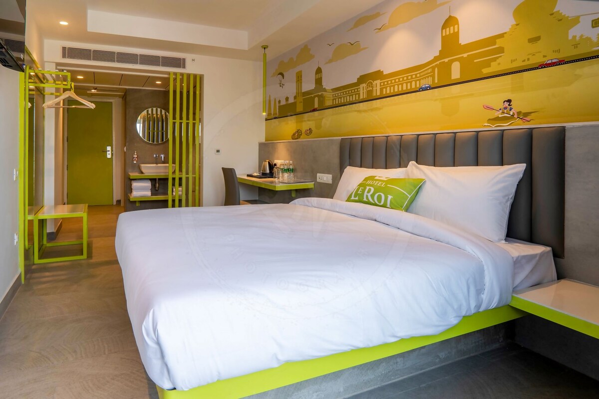 Una habitación de hotel con una cama, una mesita de noche, un espejo y un mural en la pared.