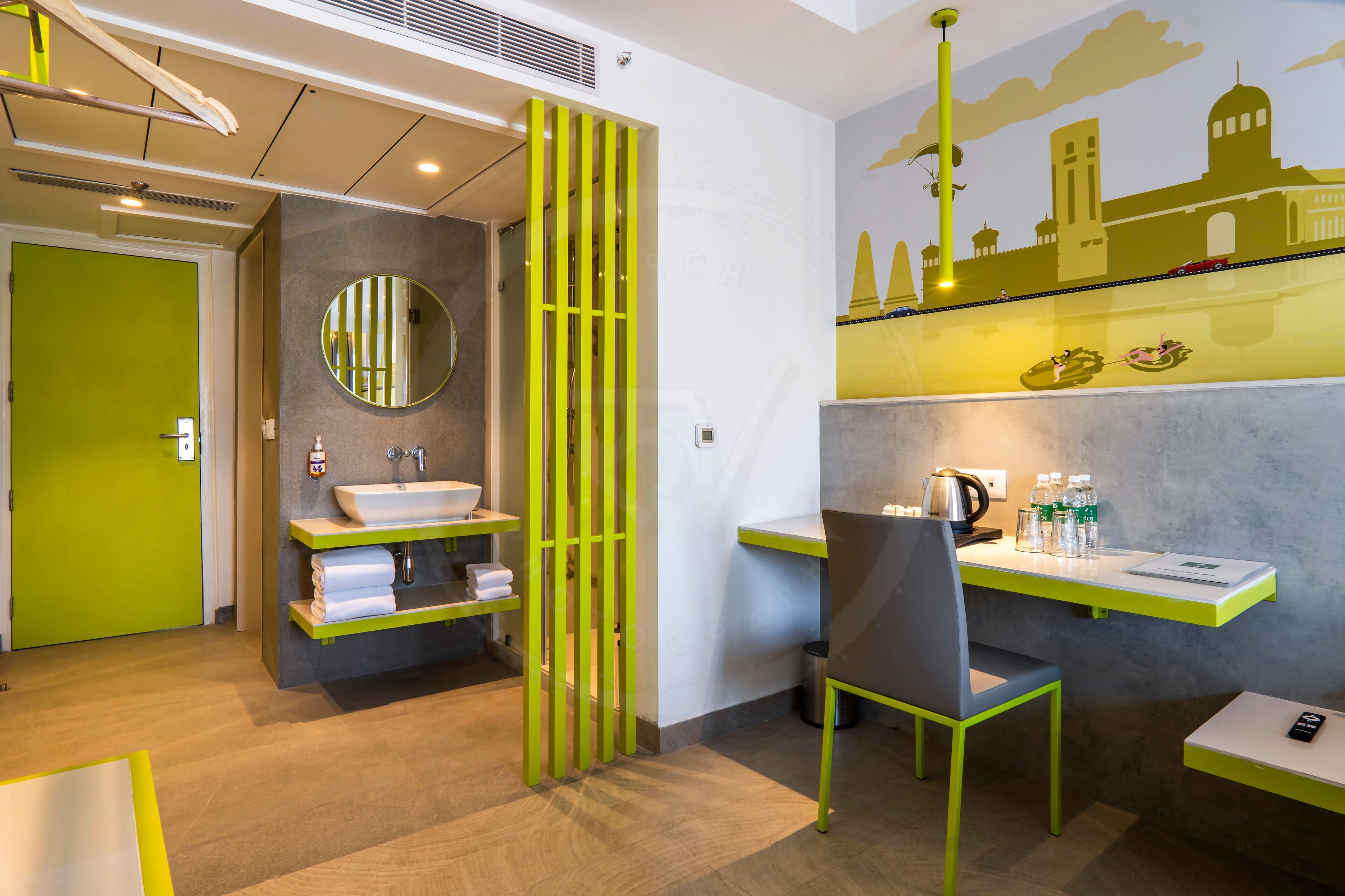 A modern bathroom with a green door, a round mirror, a sink, and a chair.