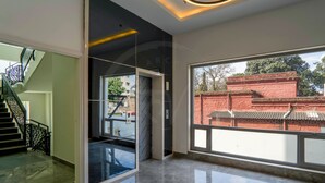 Un interior moderno con una escalera, una puerta de cristal que da al exterior y un ventanal con vistas a la arquitectura tradicional.