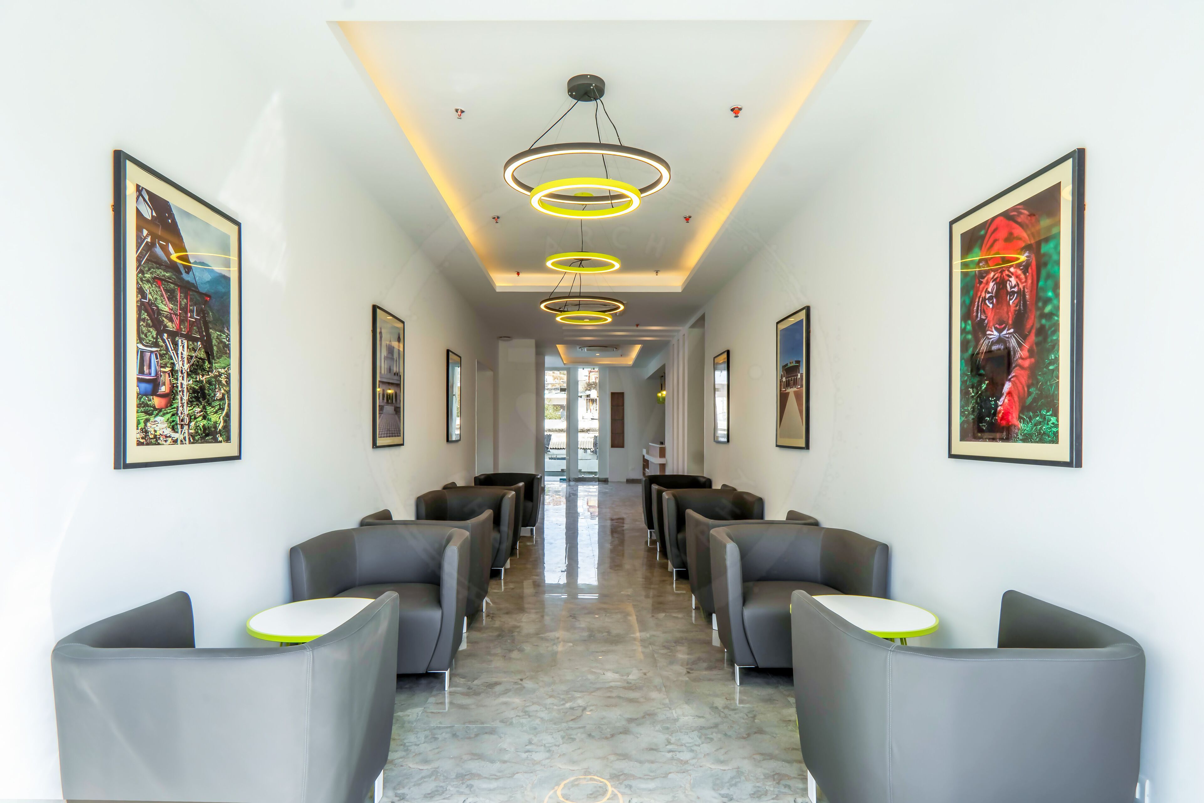 A hotel lobby with a marble floor, grey seating, and framed artwork on the walls.