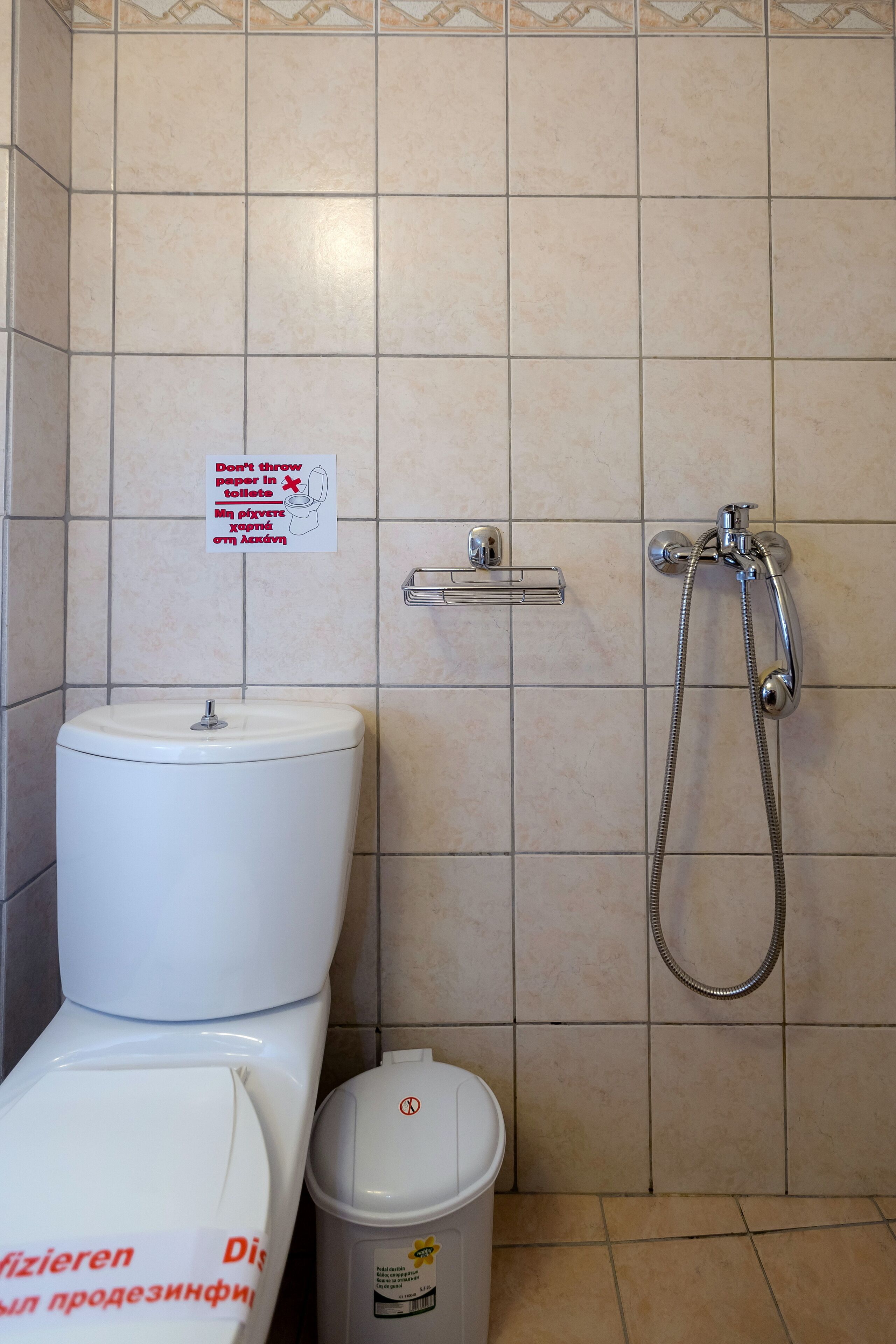 Un baño con inodoro, un cubo de basura y una ducha.