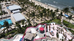 A resort with a pool, beach, and palm trees.