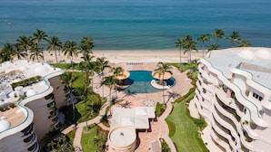 A resort with a pool, palm trees, and a beach.