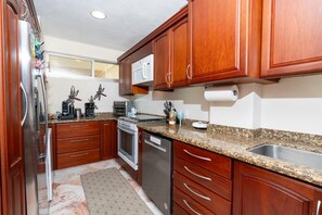 A kitchen with wooden cabinets, stainless steel appliances, and granite countertops.