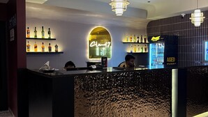 A bar area with a neon sign, shelves of liquor bottles, and a counter with a textured surface. - Club Nirvana Boutique Resort Pure-Veg (Sonapur)