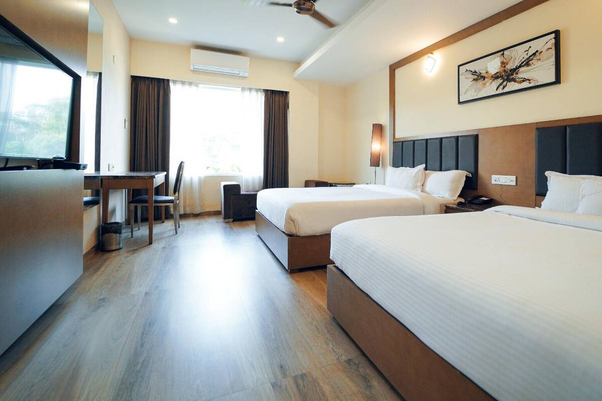 A hotel room with two beds, a desk, and a chair.