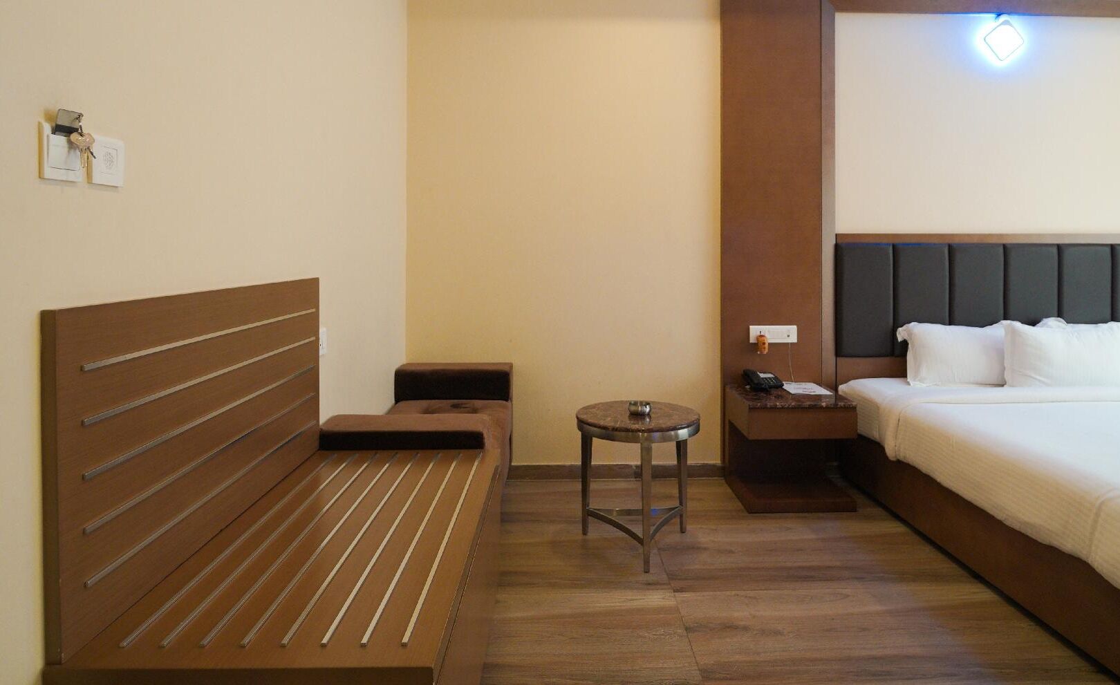 Ein Hotelzimmer mit einem Bett, einer kleinen Couch, einem runden Tisch und einem Nachttisch.