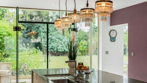Una cocina moderna con una isla grande, electrodomésticos de acero inoxidable y vistas a un jardín a través de amplias ventanas.