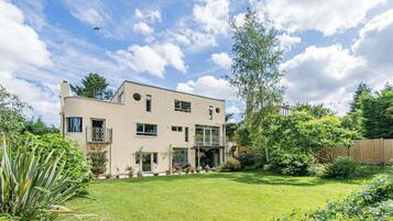 Stunning two-story building with a flat roof, surrounded by a beautifully manicured lawn and lush greenery.