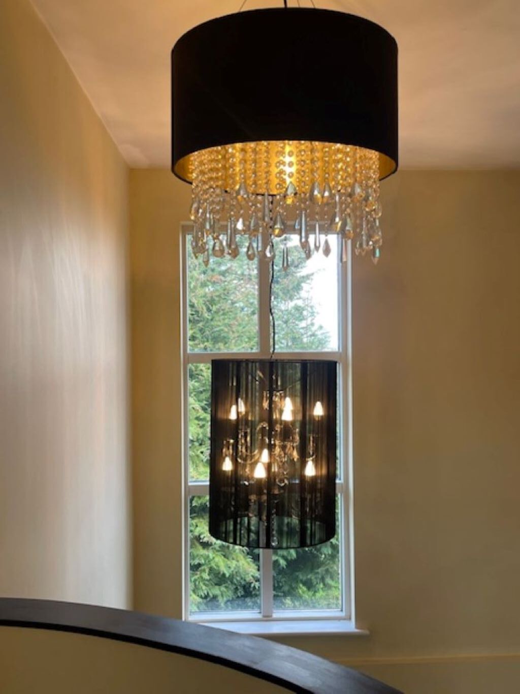 Ein Kronleuchter mit mehreren Lampen, der unter einem schwarzen, zylindrischen Lampenschirm hängt.