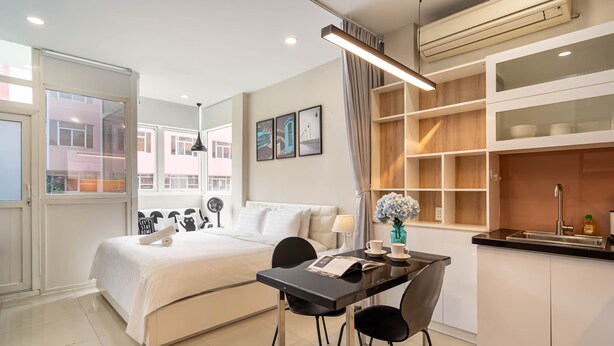 Una habitación de hotel moderna con una cama, una mesa de comedor con sillas, una zona de cocina y vistas al exterior.