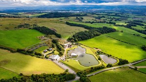 An aerial view of a rural property with a large pond, several buildings, and surrounding green fields.