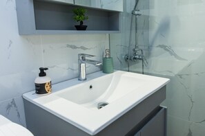 A bathroom with a white sink, a green soap dispenser, and a shower head. - Modern Cozy 1 Bd Piraeus Perfection Apt (Piraeus)