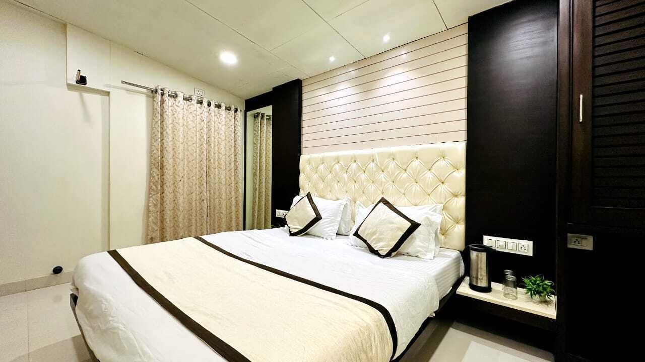A modern bedroom with a large bed, a bedside table, a dark wardrobe, and a curtain.