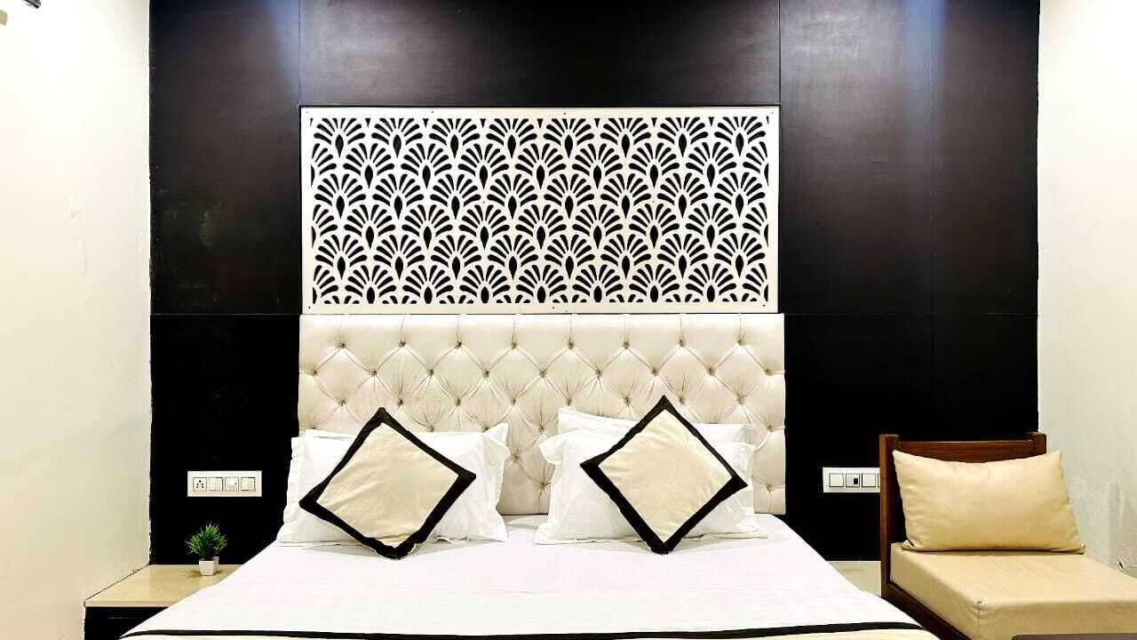 A neatly made bed with a tufted headboard, two pillows, and a decorative panel above.