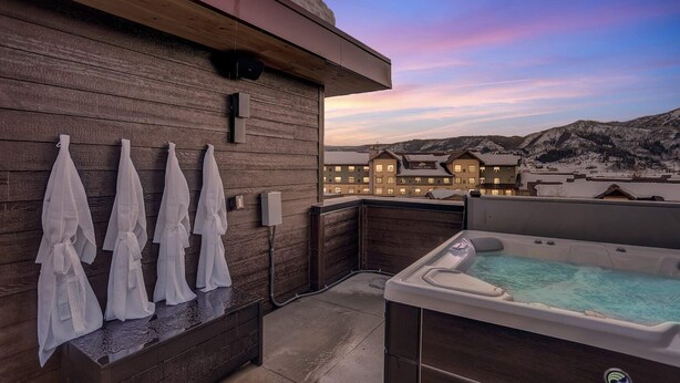 A rooftop terrace with a hot tub, wooden wall, and towels. - Luxury Townhome with Rooftop Spa and Firepit (Steamboat Springs)