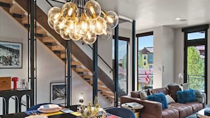 A modern dining area with a black marble table, colorful placemats, and a unique light fixture. - Luxury Townhome with Rooftop Spa and Firepit (Steamboat Springs)