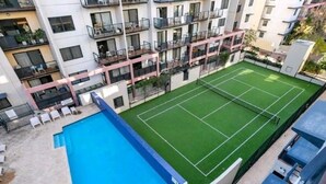 Ein Wohngebäude mit Tennisplatz und Swimmingpool.