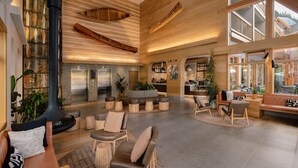 Eine großzügige Lobby mit Holzbalken, Sitzbereichen und einer modernen Küche im Hintergrund.