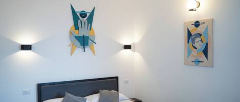 A modern bedroom with a bed, two bedside tables, and abstract wall art.