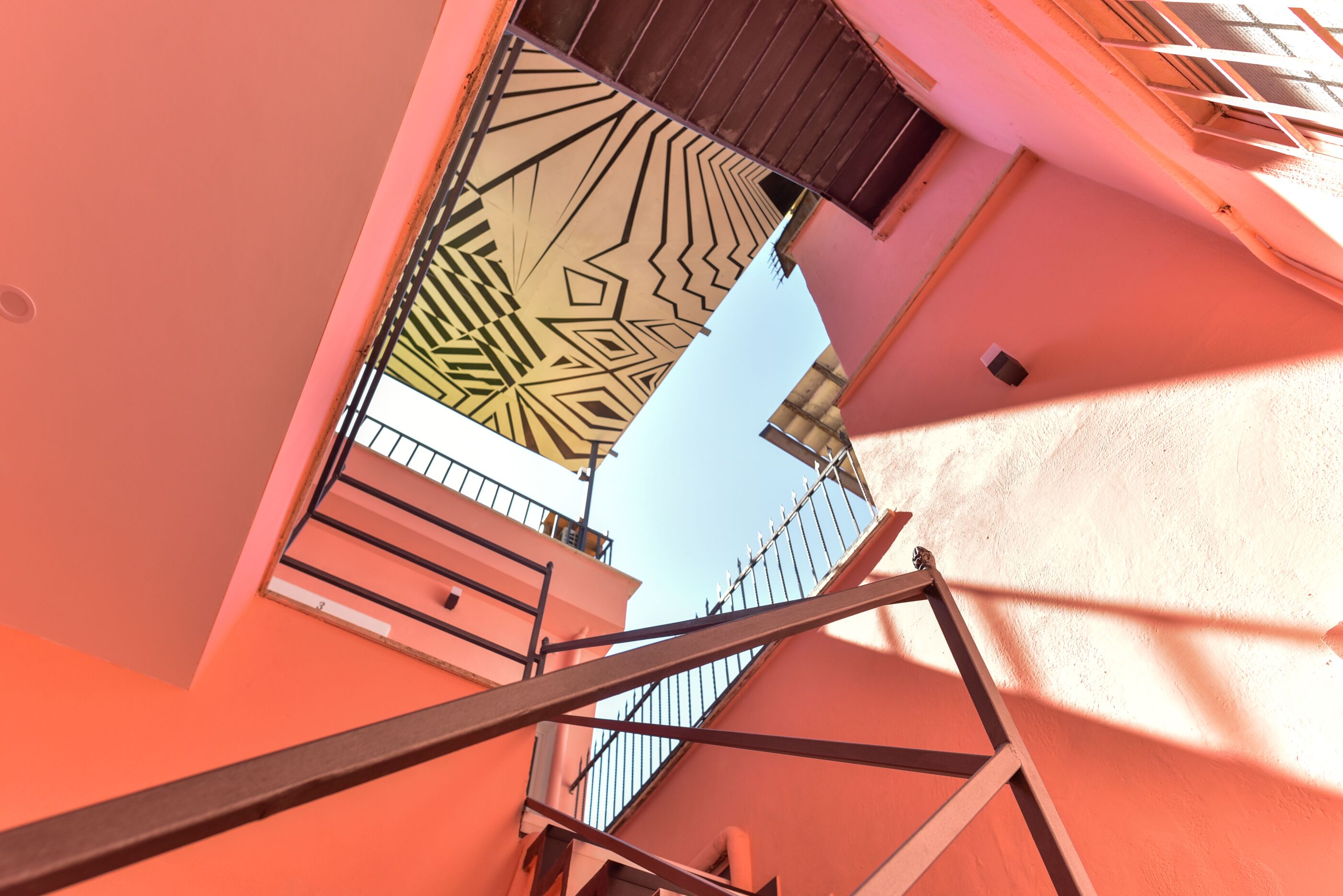 A staircase leading to a balcony with a geometric patterned door.