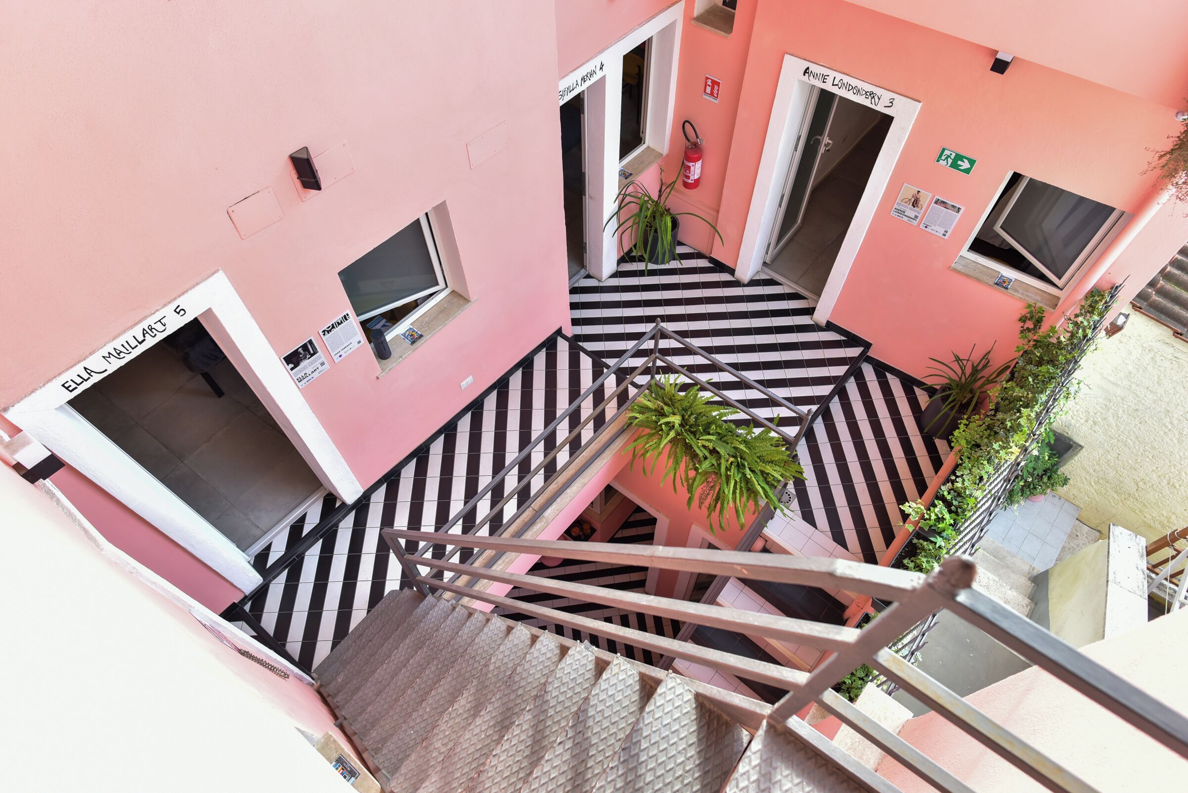 A pink building with multiple doors, a staircase, and a fire extinguisher.