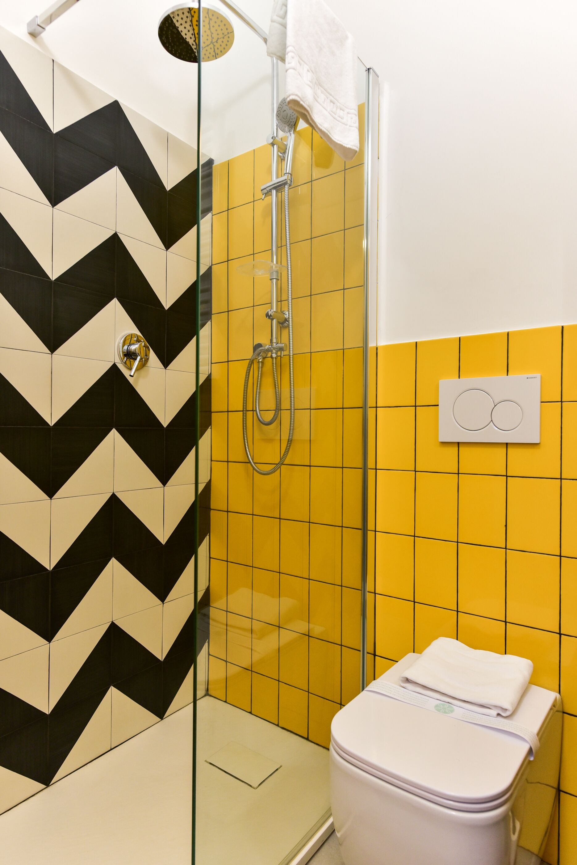 A bathroom with a shower, toilet, and a wall with a chevron pattern.
