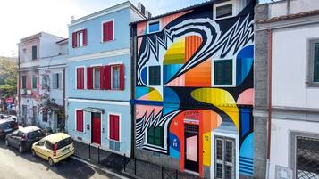 A colorful building with a vibrant mural, a red door, and a sign for Fanfull Art Guest House.