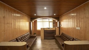 Un interior de madera con una mesa de recepción, dos sofás y un banco.