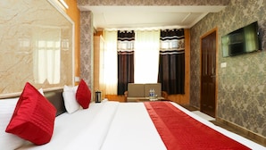 Habitación de hotel con una cama grande, un televisor montado en la pared y vistas al exterior a través de la ventana.