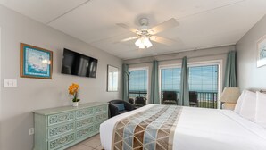 Una habitación de hotel con cama, tocador, televisor y balcón con vistas.
