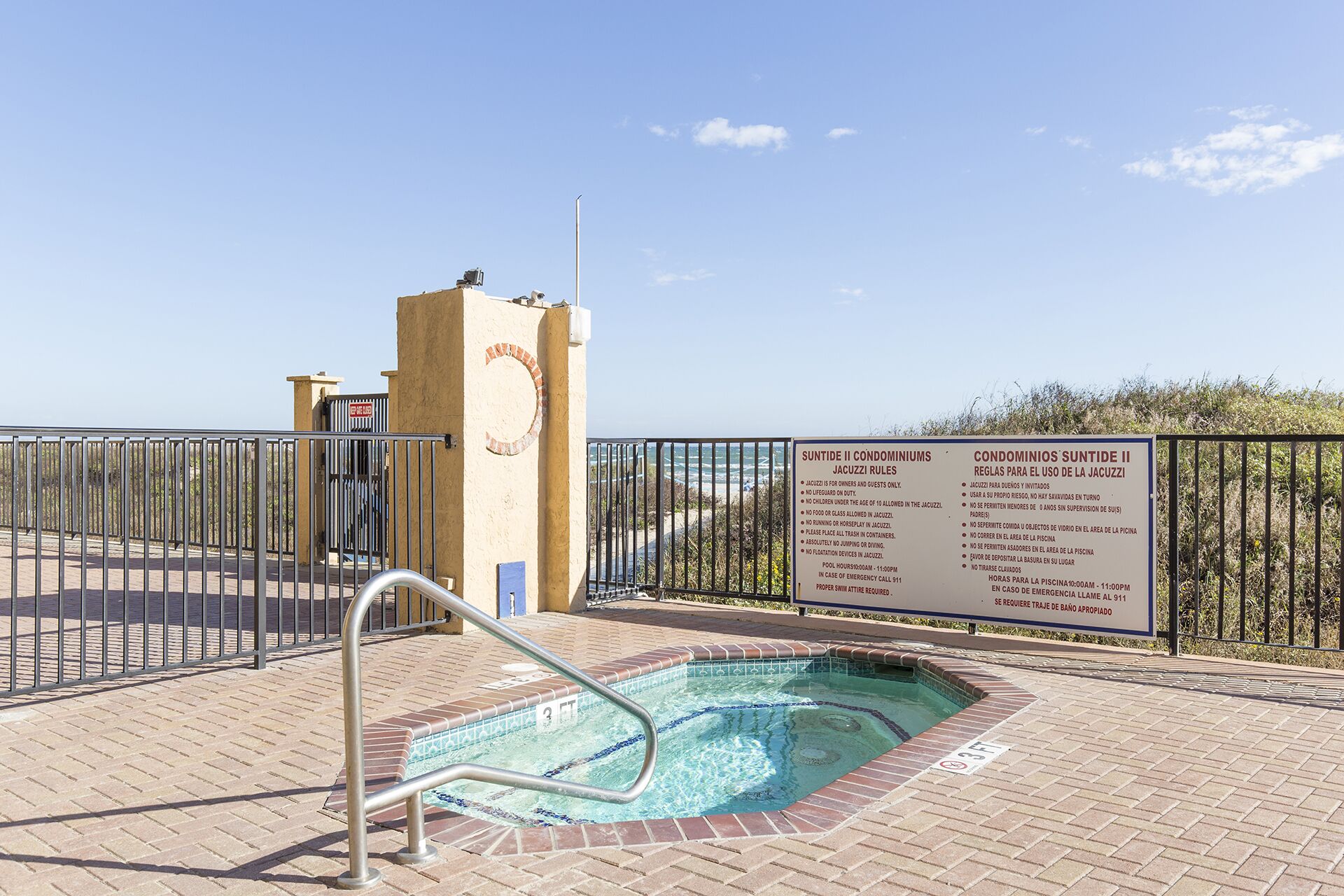 A pool area with a sign detailing rules for the use of the jacuzzi.