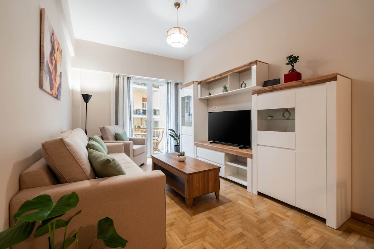 A modern living room with a sofa, coffee table, TV, and built-in shelving.