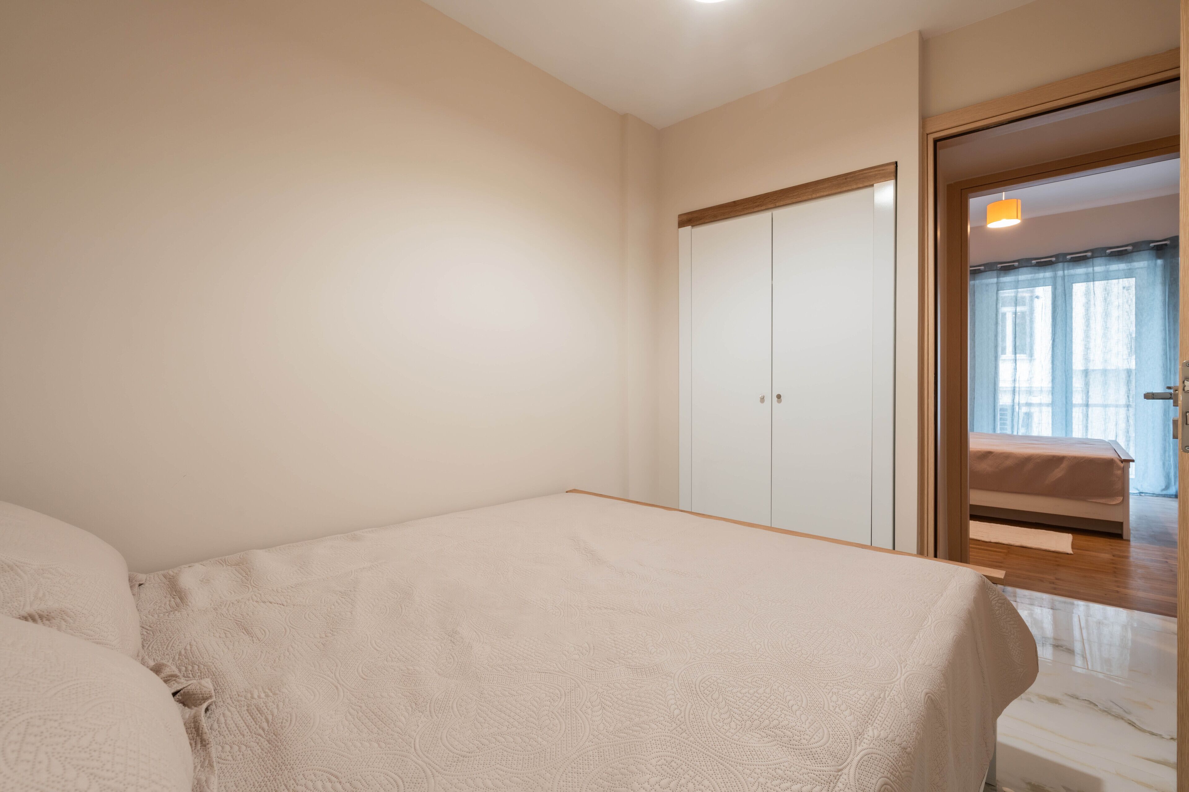 A bedroom with a bed, a wardrobe, and a door leading to another room.
