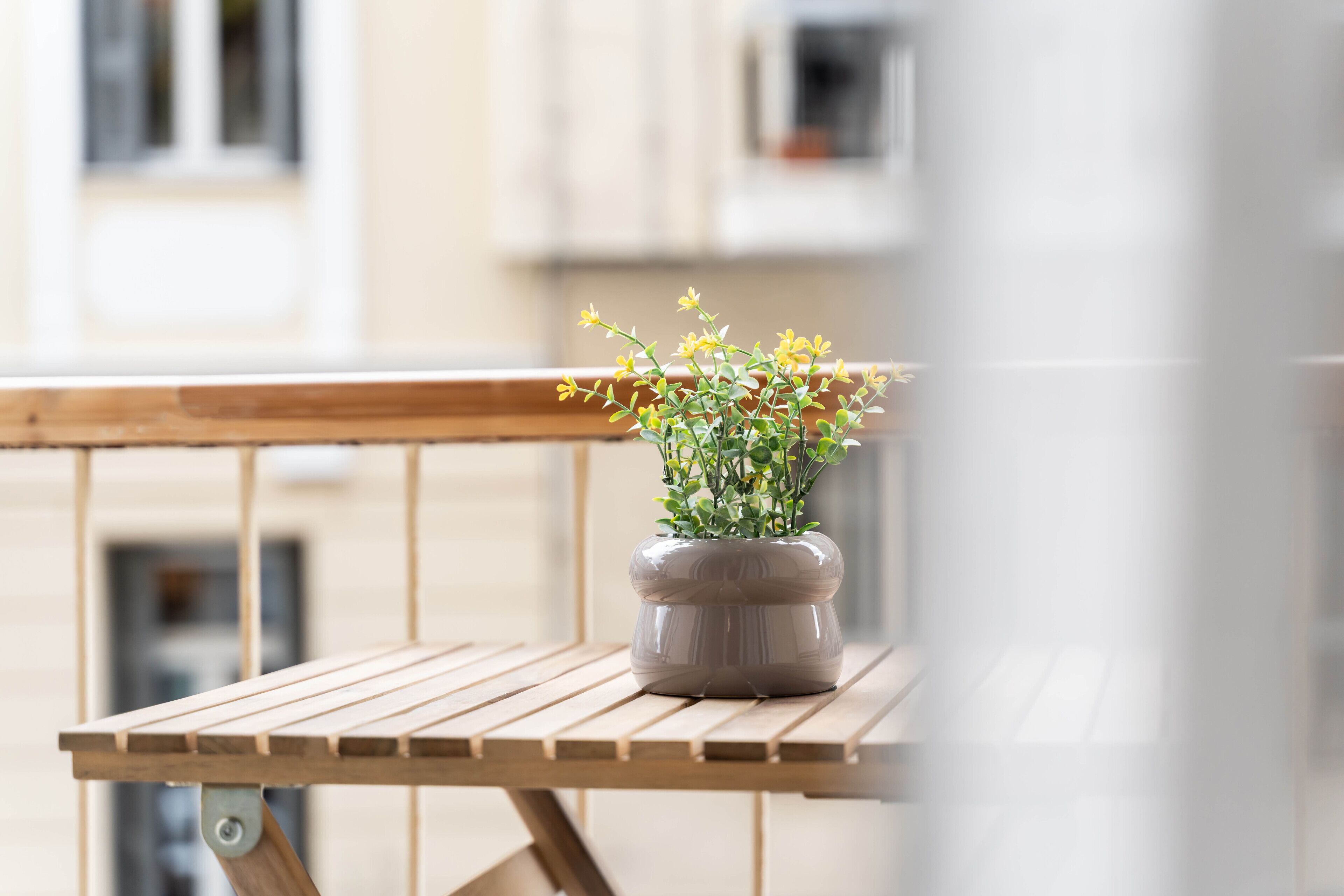 Uma mesa de madeira com uma planta em vaso numa varanda.