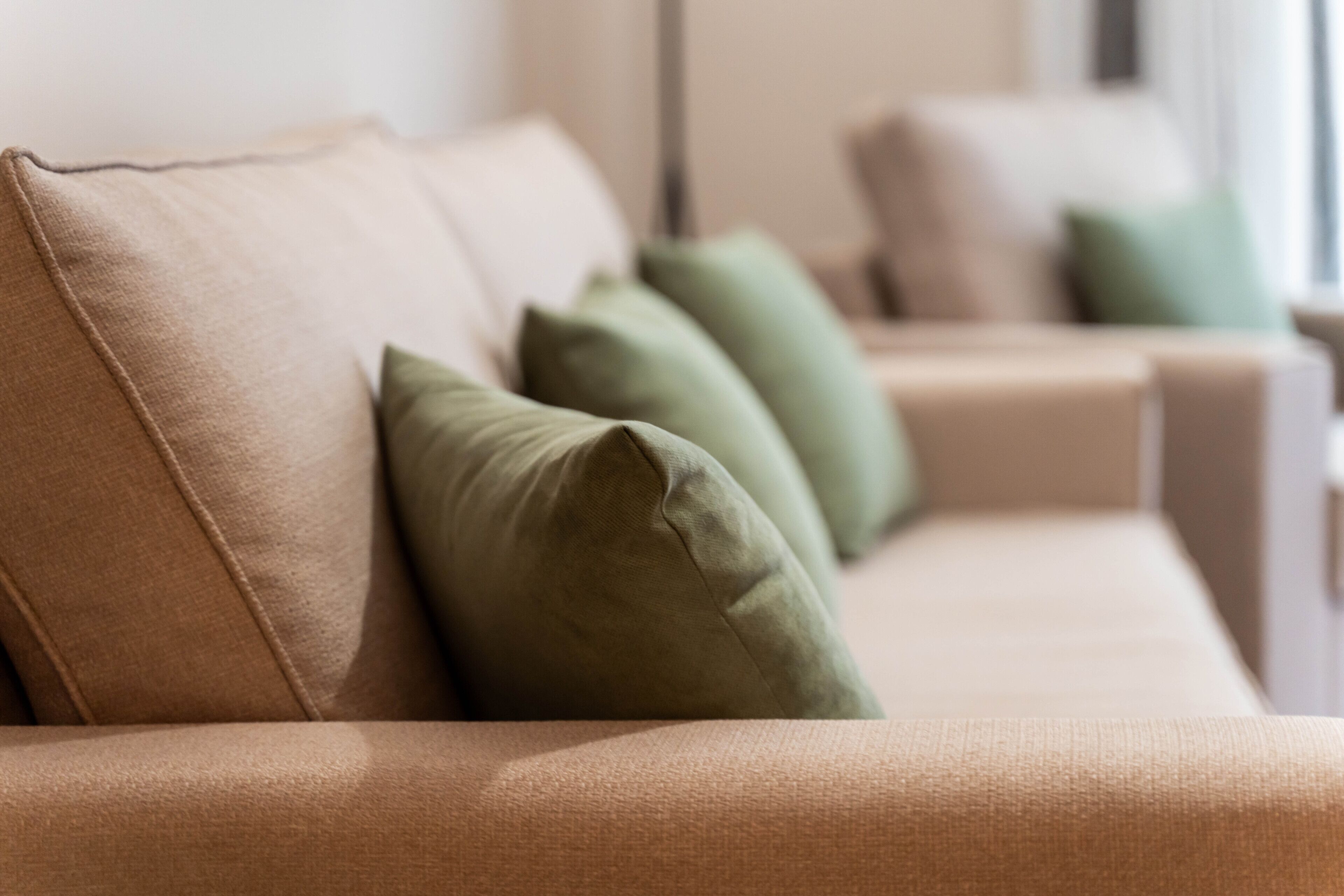 A beige sofa with green cushions.