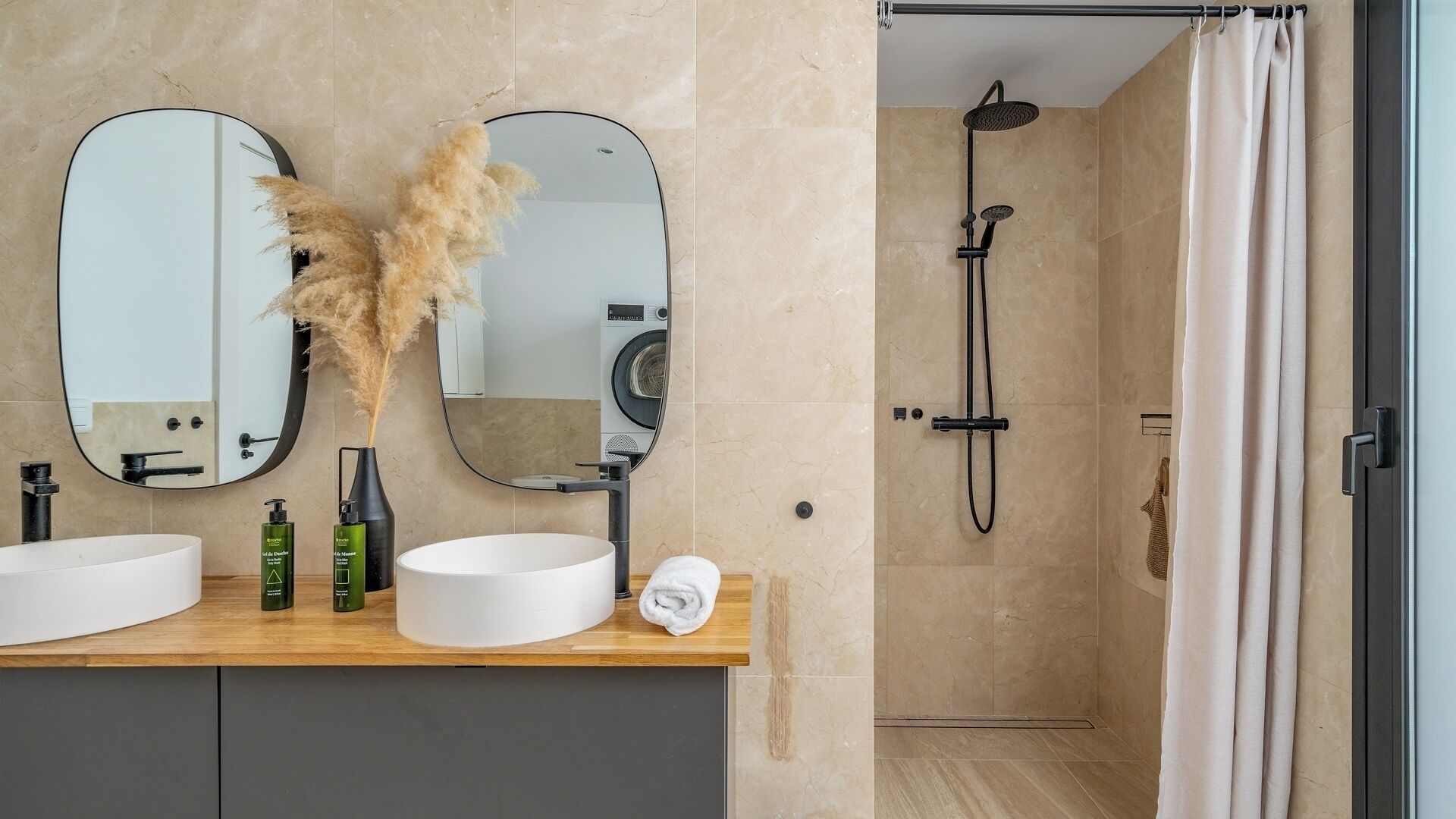 Een badkamer met twee wasbakken, een spiegel, een douche en een handdoek.