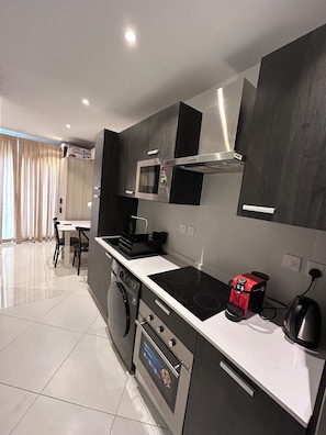 A modern kitchen with a built-in oven, microwave, and a coffee machine. - One Bedroom Studio Apartment at The Lennox Airport Residential Accra (Accra)