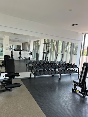 A gym with exercise equipment, a mirror, and large windows. - One Bedroom Studio Apartment at The Lennox Airport Residential Accra (Accra)