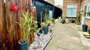 A narrow pathway flanked by a wooden fence with a butterfly decoration and potted plants. - March-2bed Apt - Family Friendly - Pet Friendly (March)