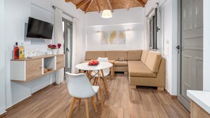 Una sala moderna con techo de madera, un televisor de pantalla plana, un sofá, una mesa de comedor con sillas y un pequeño armario blanco.