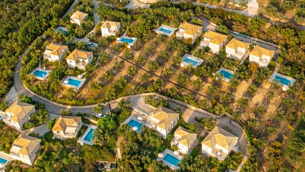 Vista aérea de una zona residencial con casas, piscinas y un paisaje montañoso.
