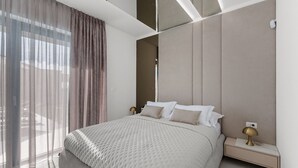 Une chambre moderne avec un grand lit, une table de chevet et une vue sur l’extérieur.