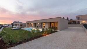 Une maison moderne dotée d’une piscine, d’un patio et d’un jardin bien entretenu.