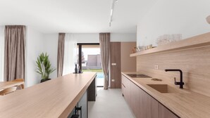 Une cuisine moderne avec des plans de travail en bois, un évier encastré et une vue sur l’extérieur.