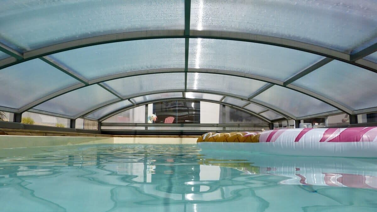 An indoor swimming pool with a glass ceiling, clear water, and a pink and white inflatable pool border.