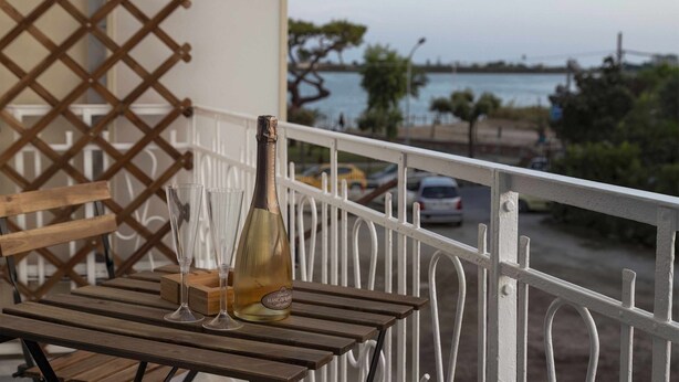 Un balcone con un tavolo di legno, una bottiglia di vino e due bicchieri.