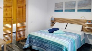 Una camera da letto con un letto, una testata in legno e vista mare dalla finestra.