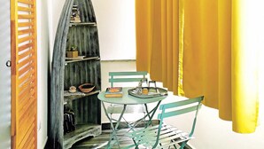 Una stanza con una porta in legno, uno scaffale curvo, un tavolo con sedie e tende gialle.