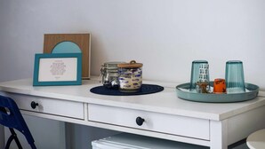 A white desk with a framed certificate, a glass jar with a lid, and two glass cups on a teal tray. - B&B Angelica - Blue (Bacoli)